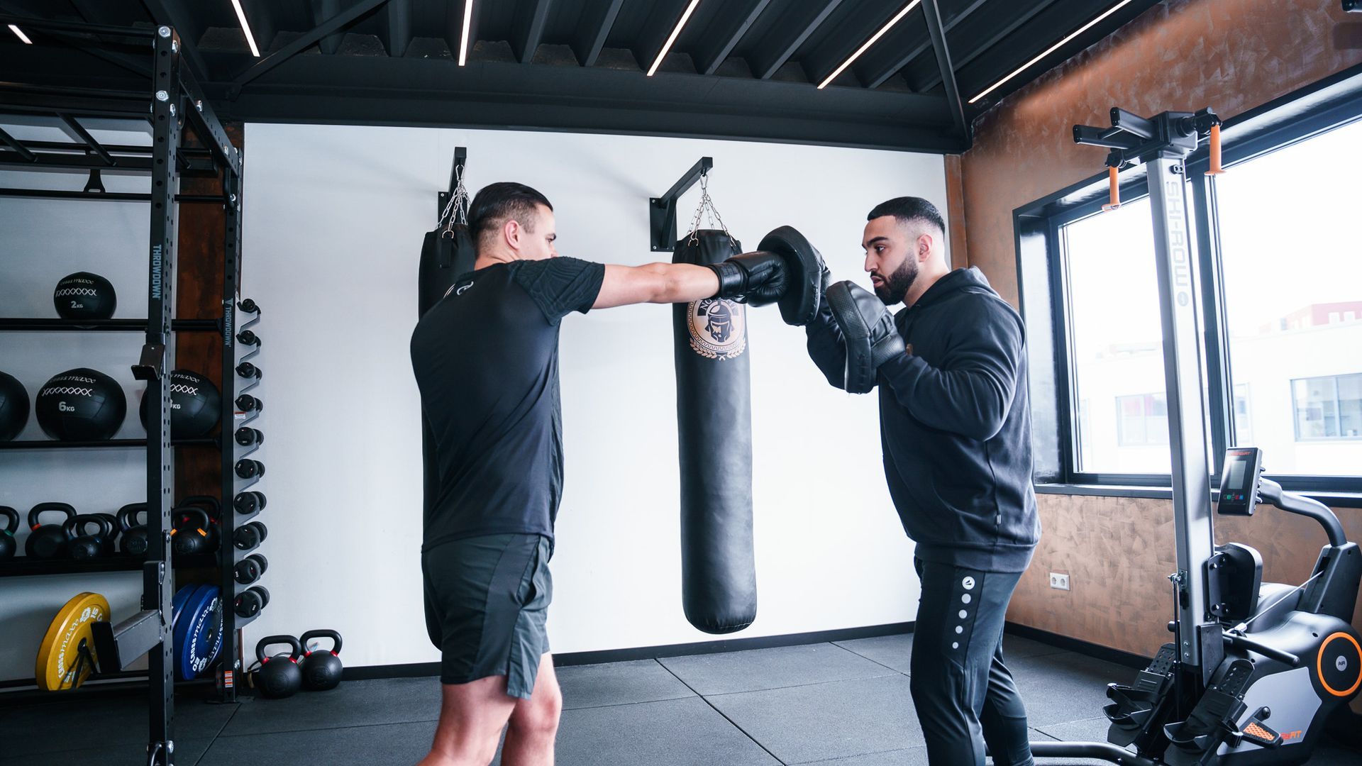 Twee mannen beoefenen boksen in een sportschool.
