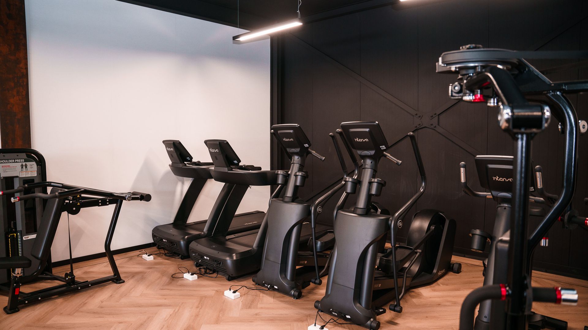 Een rij loopbanden en elliptische trainers in een sportschool.