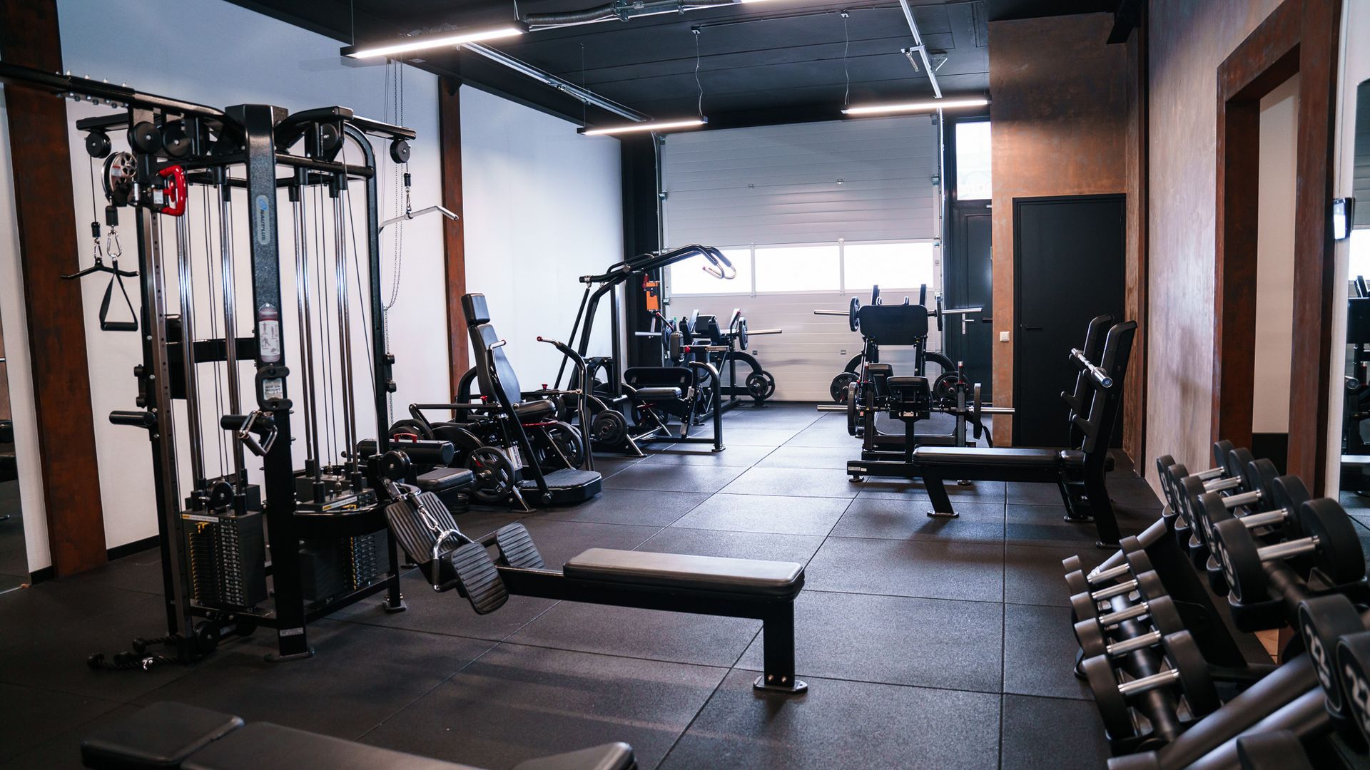 Een sportschool vol met veel fitnessapparatuur en dumbbells.