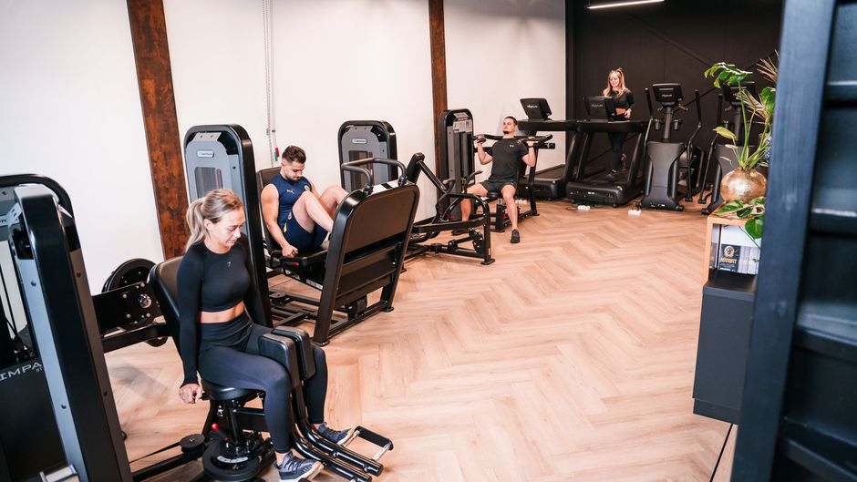 Een vrouw zit op een machine in een sportschool.