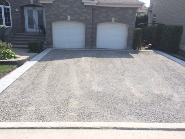 Une allée devant une maison avec deux portes de garage