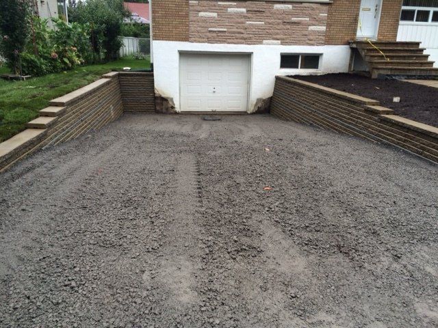 Une allée de gravier menant à un garage avec un mur de briques