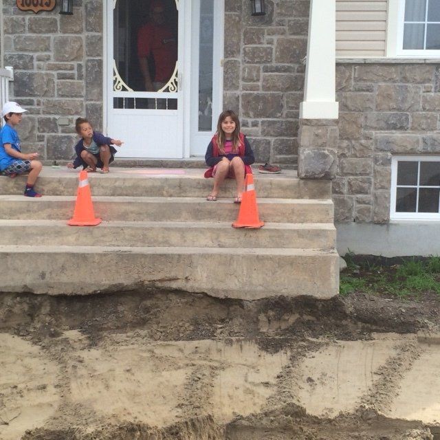 Trois enfants sont assis sur les marches d'une maison