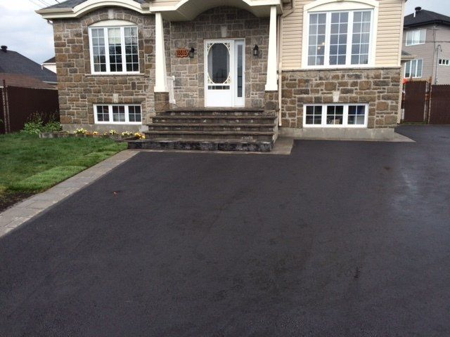 Une maison en briques avec une allée noire devant elle