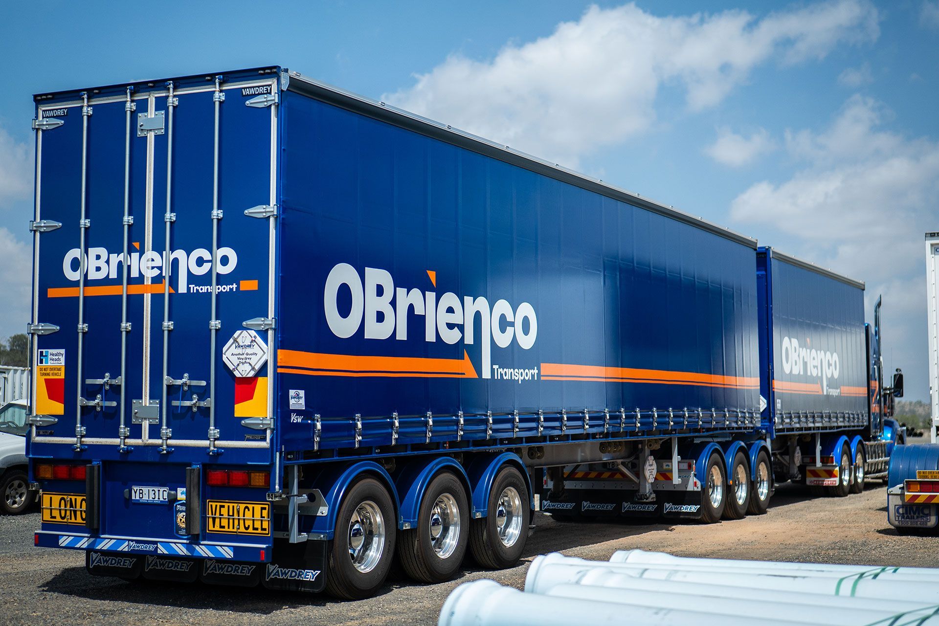 Blue O'Brienco Transport semi-truck trailer with white and orange lettering under a cloudy sky.