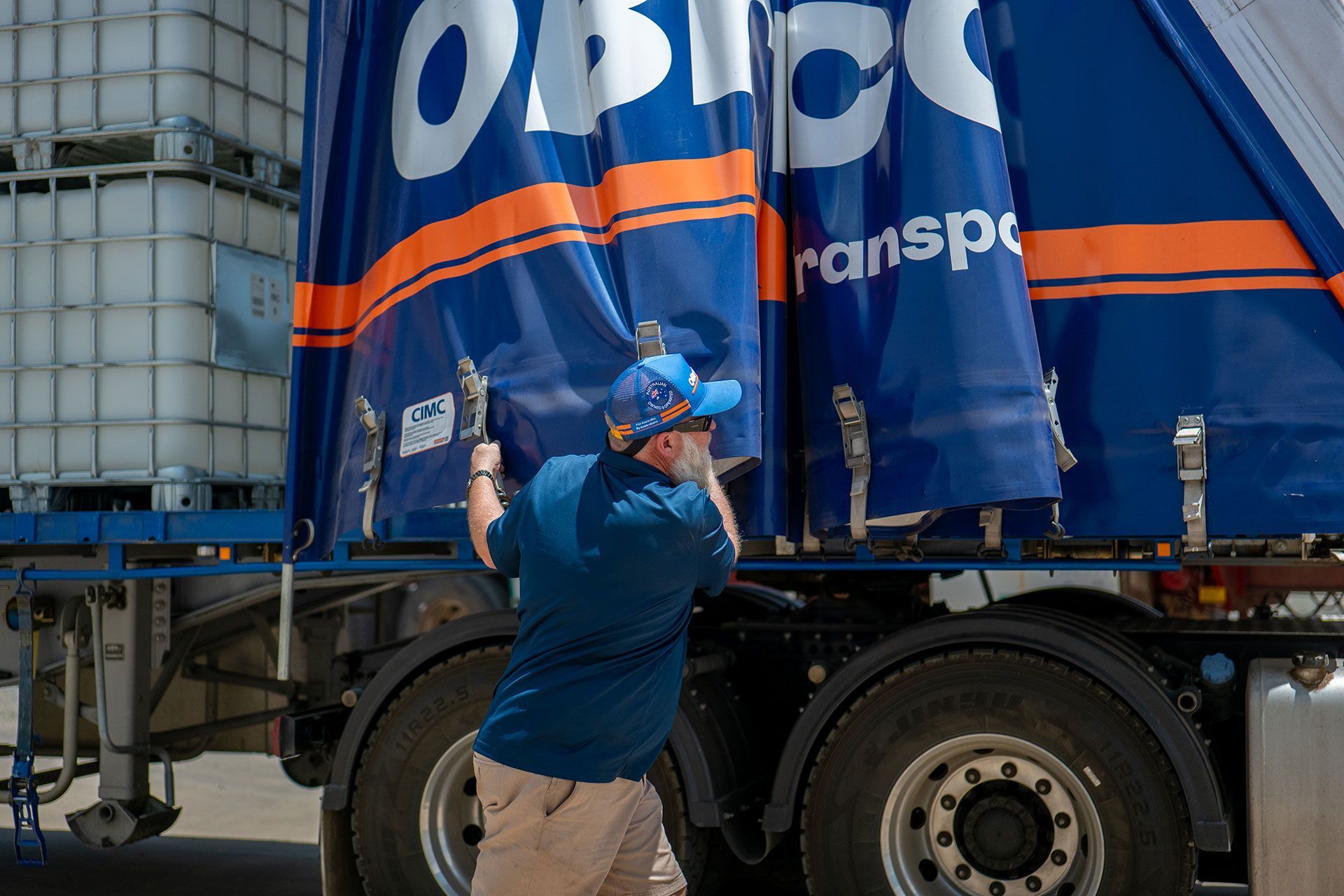 Person secures tarp on truck with