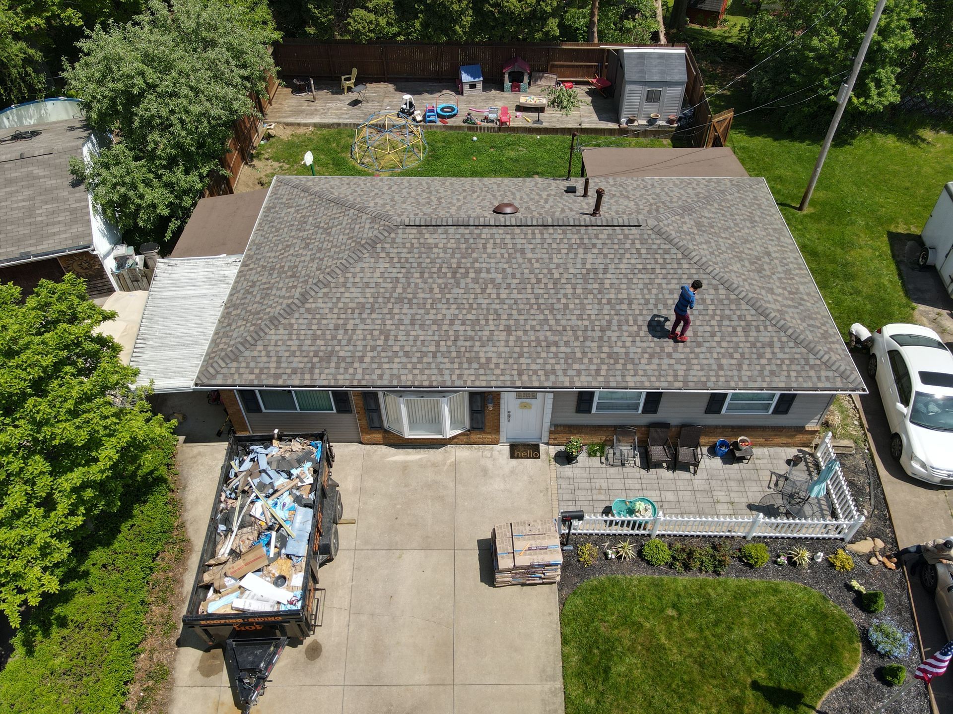 An aerial view of a house with a man standing on the roof