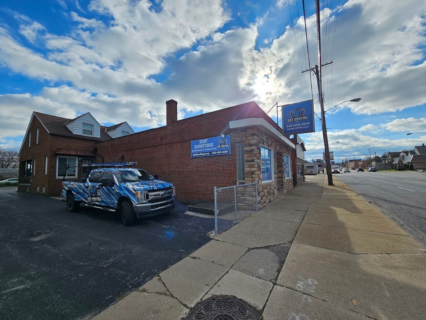 Three trucks are parked in front of a building that says roofing