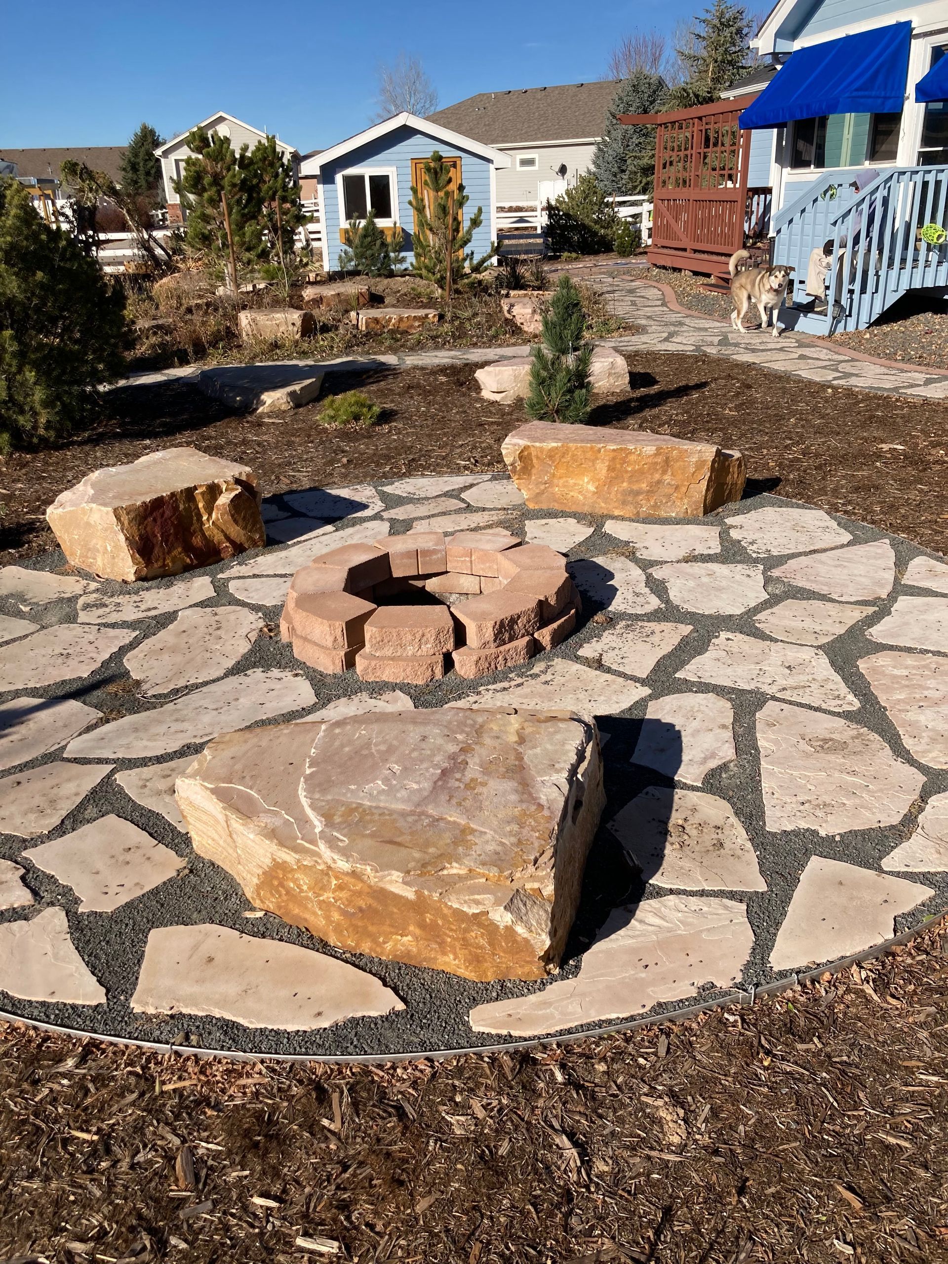 A fire pit is surrounded by rocks in a backyard.