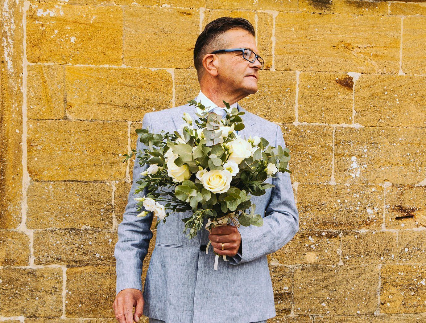 A man in a suit is holding a bouquet of flowers.