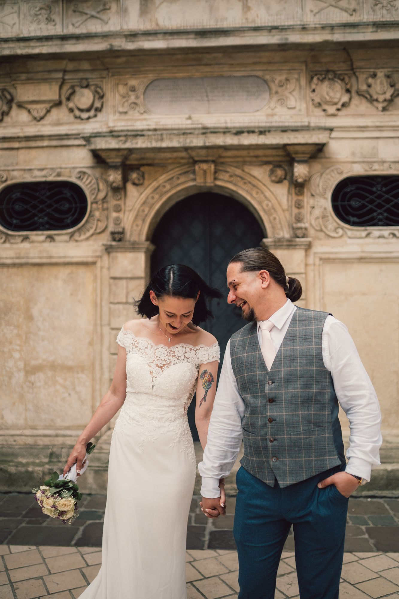 A bride and groom are holding hands in front of a building.