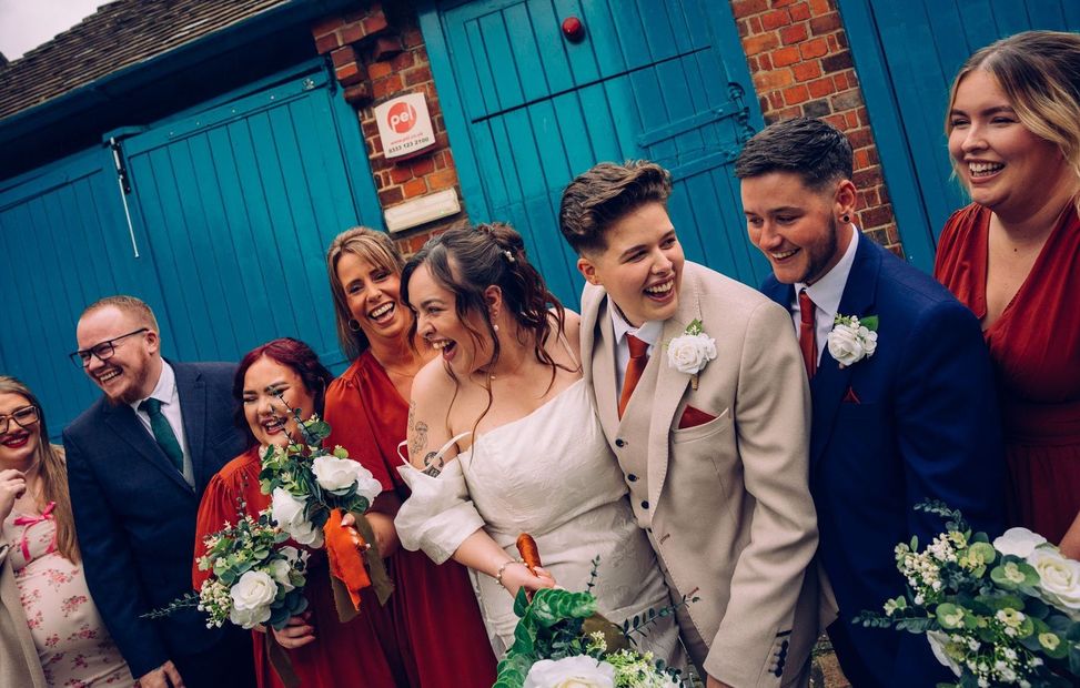 A couple are posing for a picture with their wedding party.