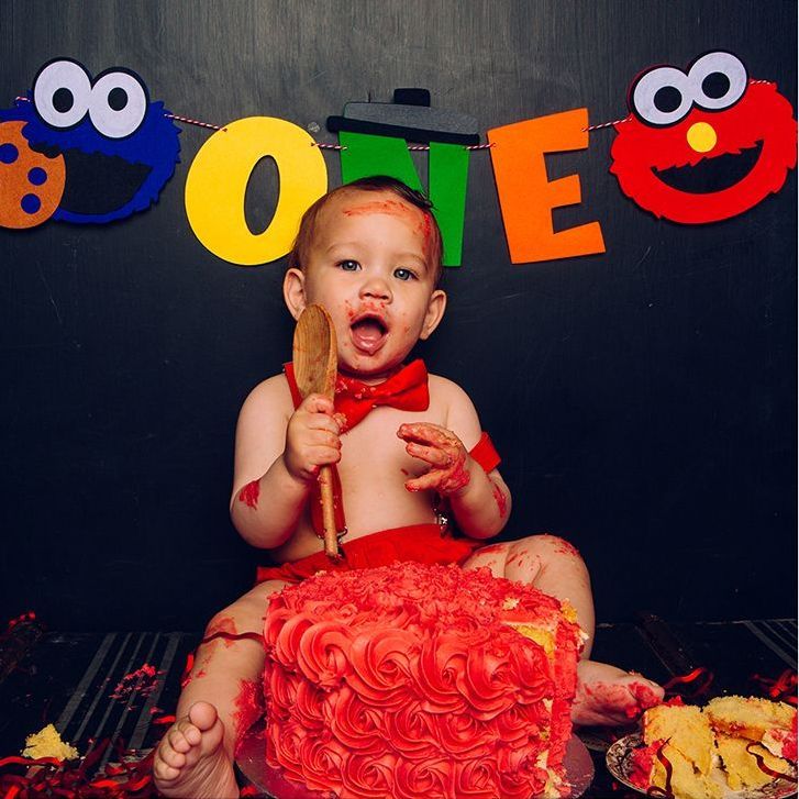 A baby is sitting in front of a sesame street cake