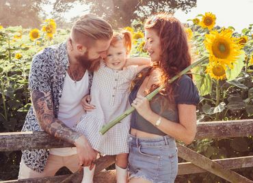 A family is posing for a picture in a field of sunflowers.