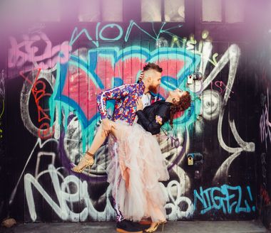Couple kissing in front of a graffiti wall