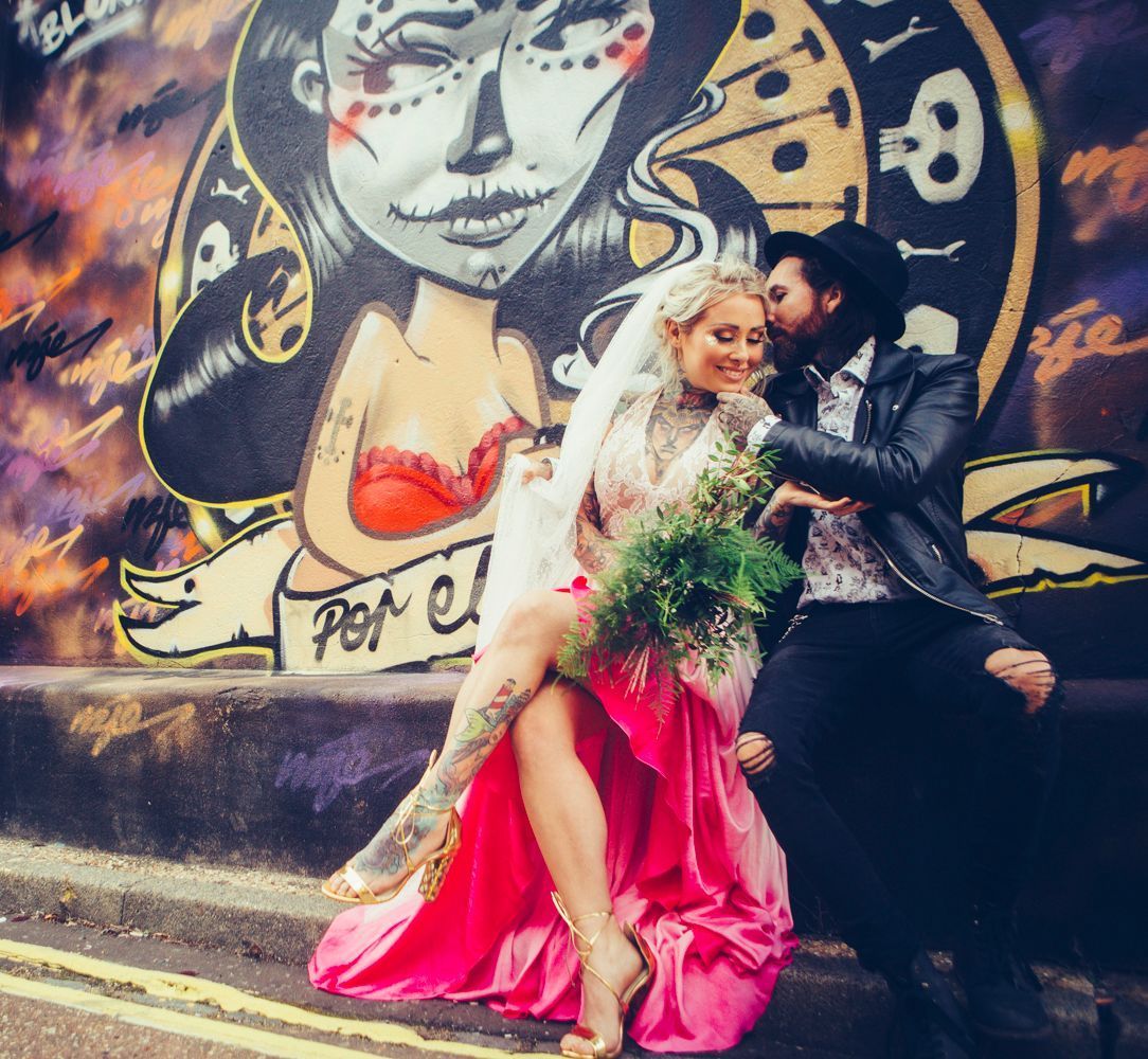 A bride and groom are posing for a picture in front of a mural that says peace