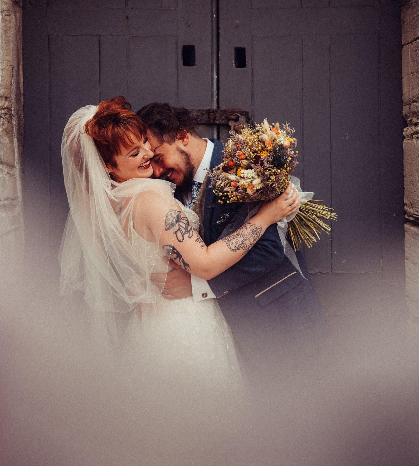 A bride and groom are sitting at a table signing a wedding certificate.