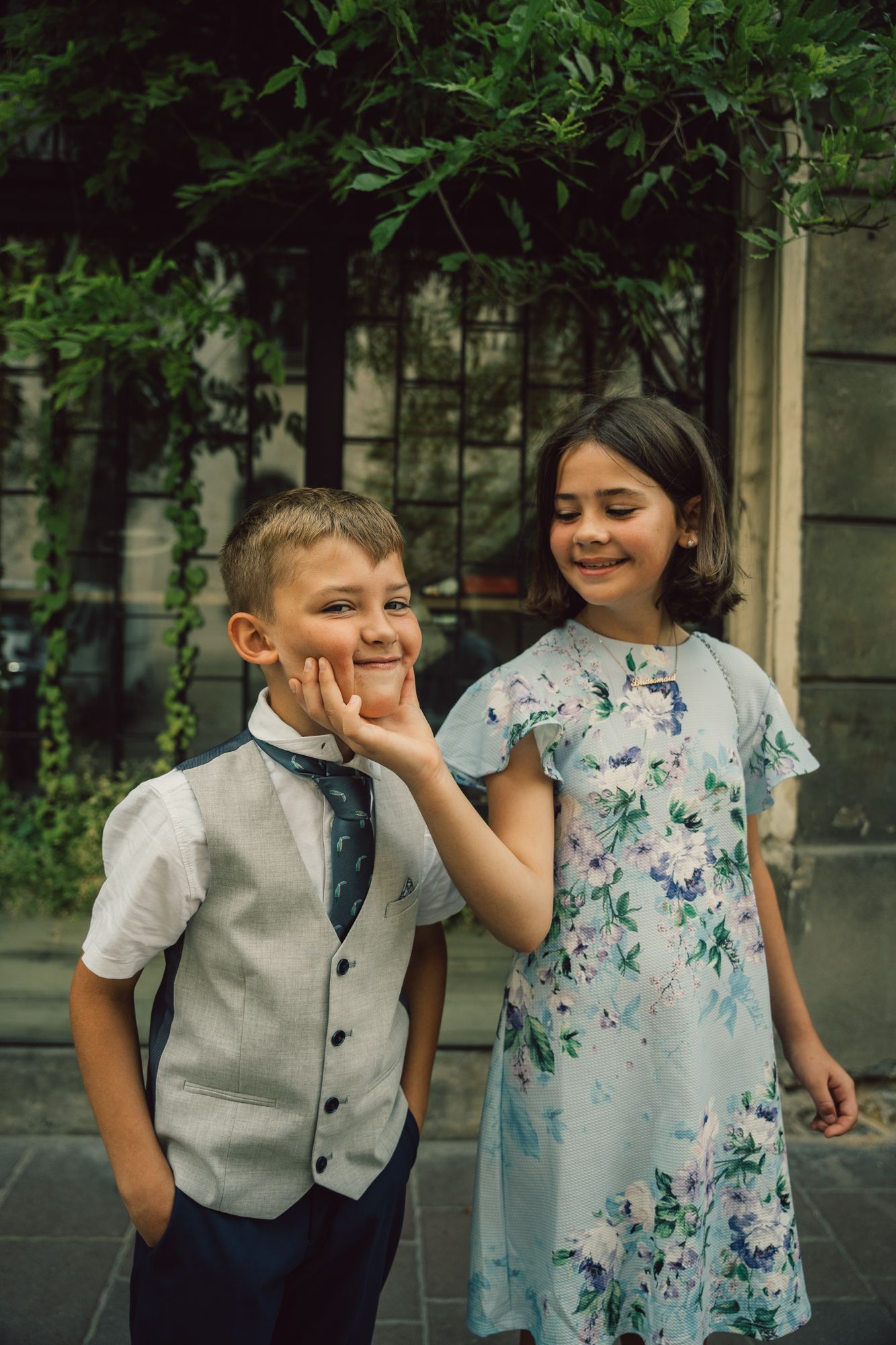 A boy and a girl are standing next to each other on a sidewalk.
