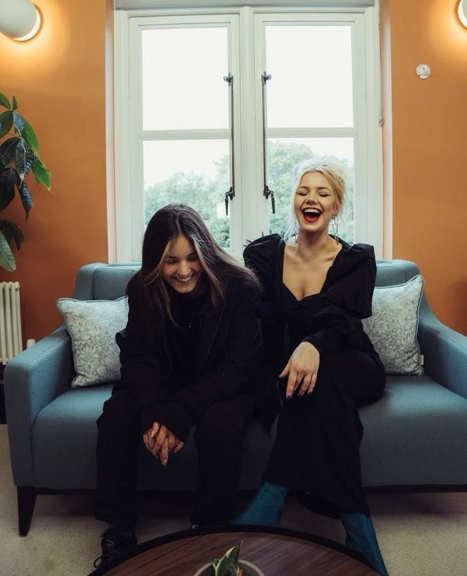 Two women are sitting on a couch and laughing