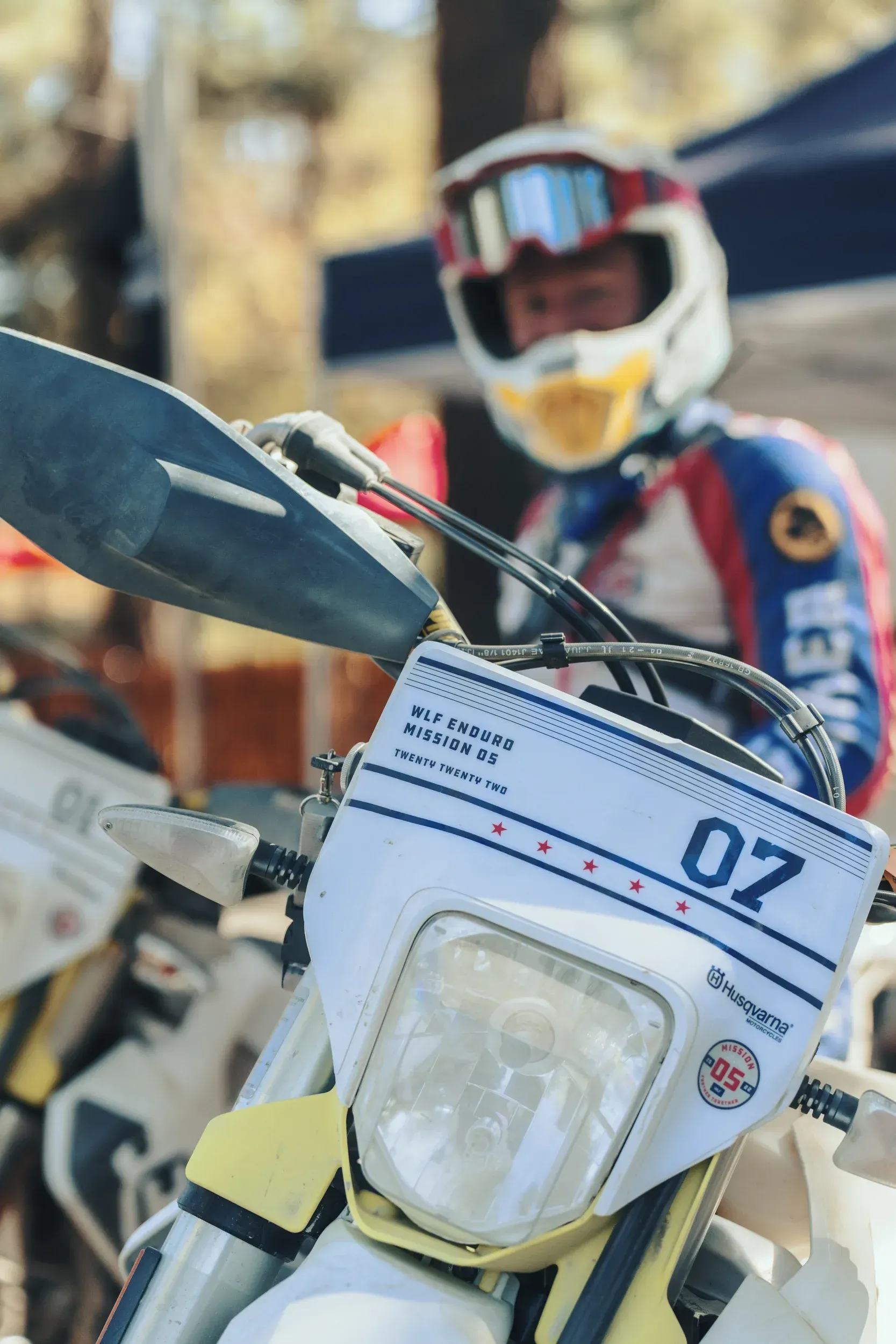 Motorcycle rider in helmet, behind the handlebars, with motorcycle's headlight and number plate.