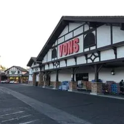 Exterior of a Vons grocery store with a dark brown and white facade. The sky is visible above.