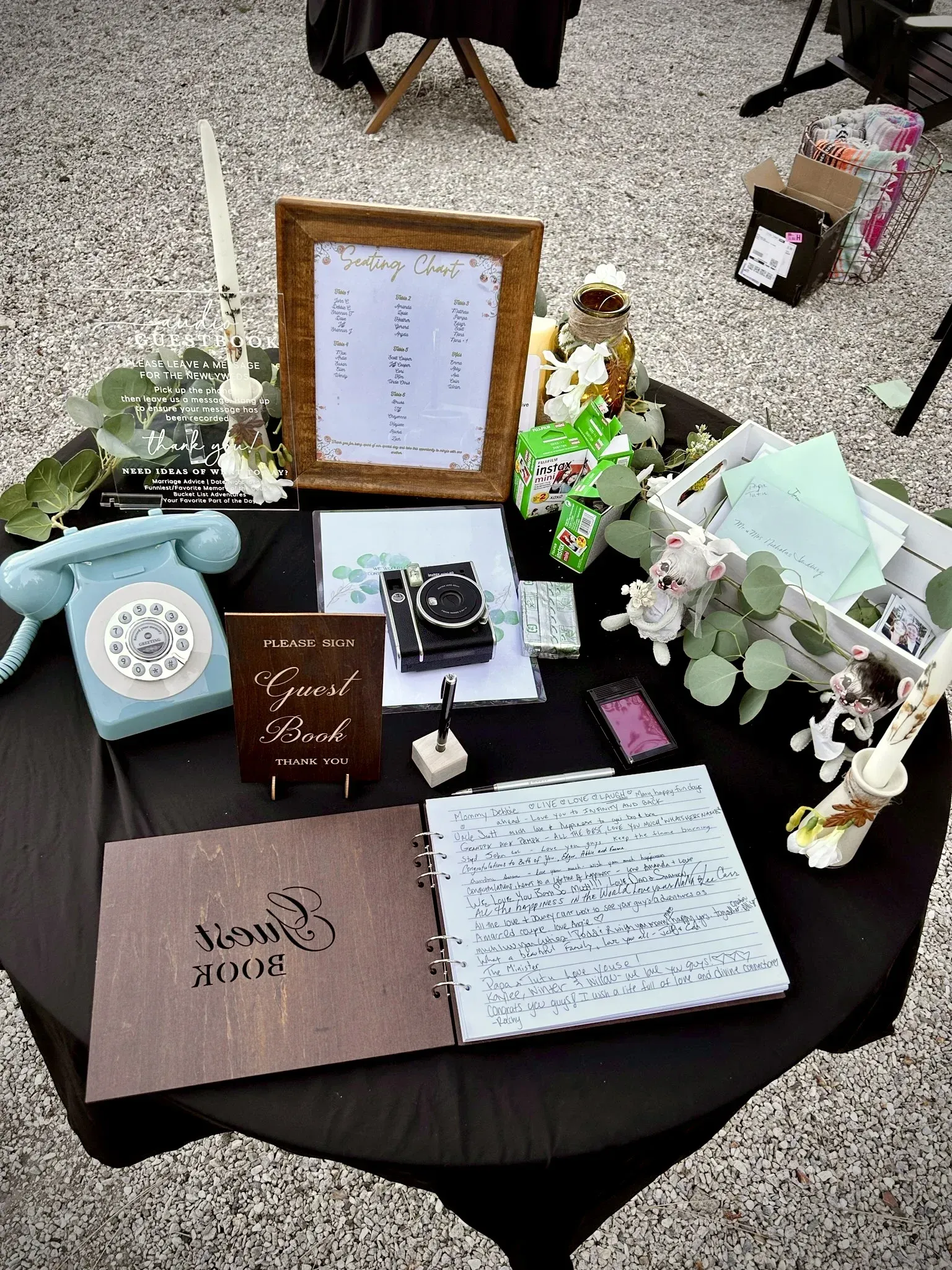 Wedding guest table with guest book, telephone, and framed sign on black cloth.