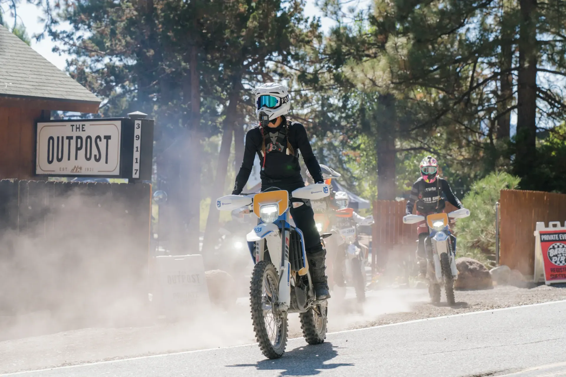 Motorcyclists riding on a dusty road towards an 