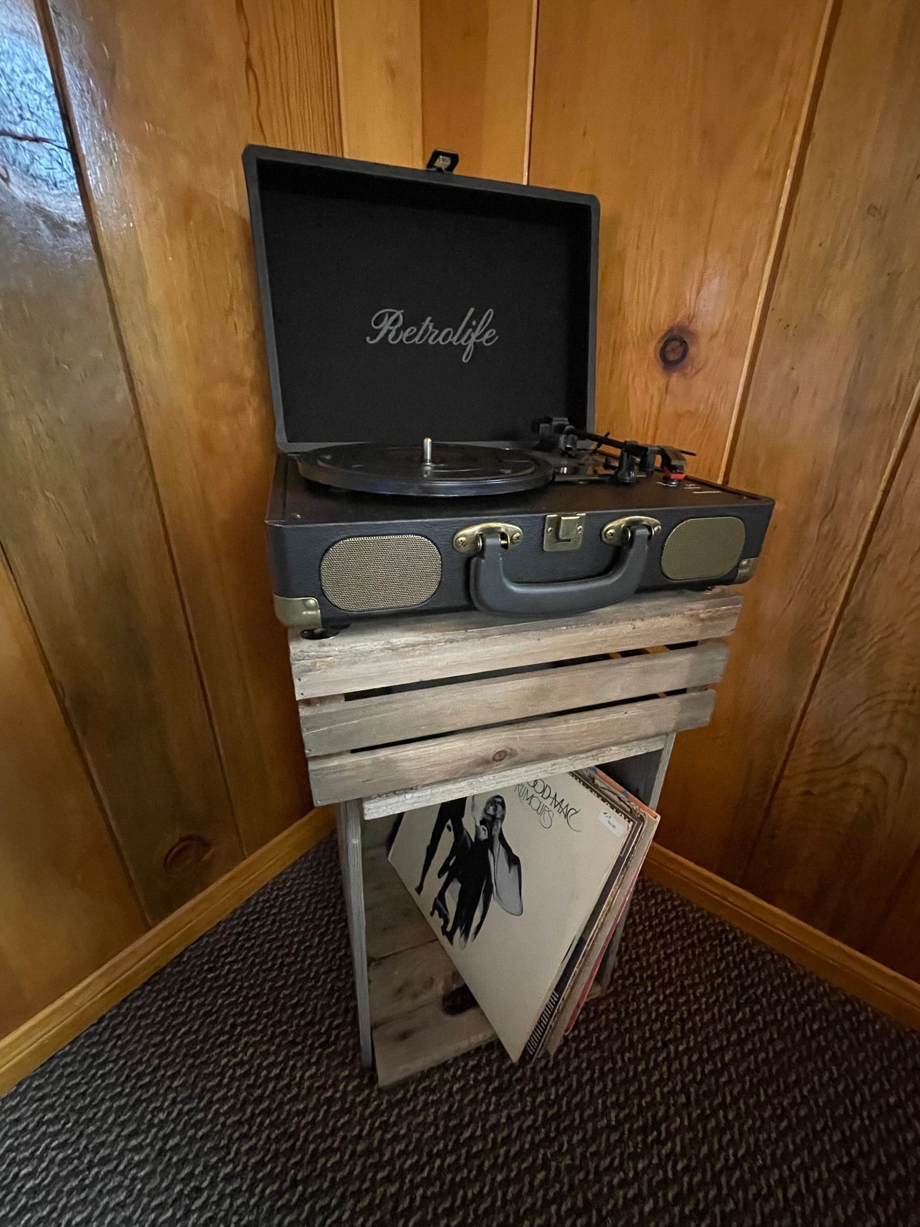 Record player on wooden crates in a corner, with vinyl records visible below.
