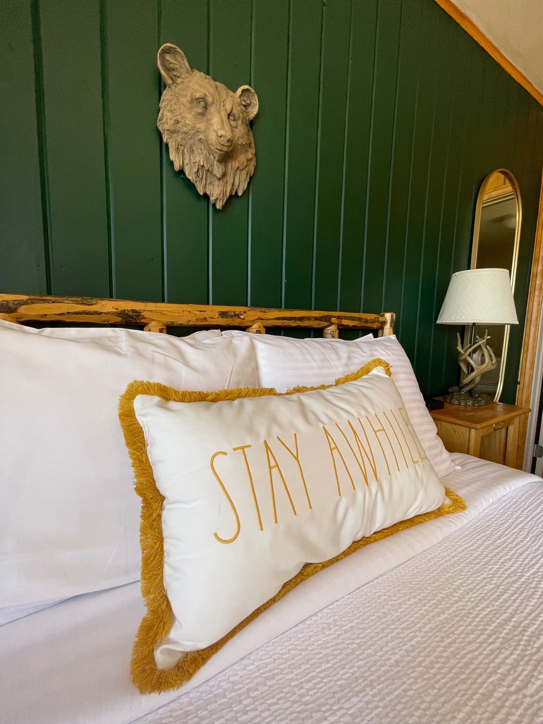 Bedroom with green paneled wall, bear head art, bed with 