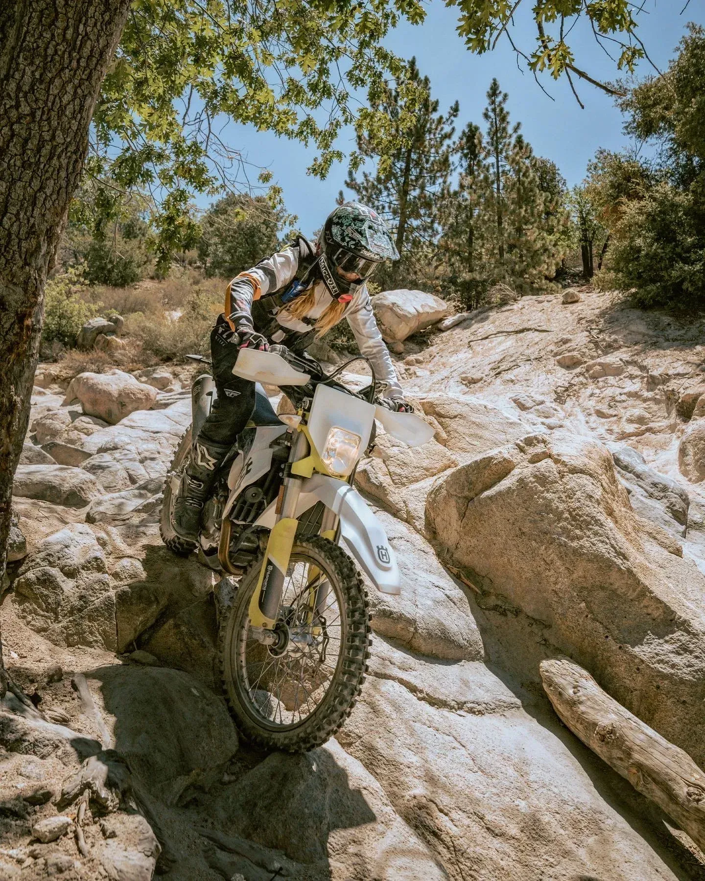 Person riding a motorcycle over rocky terrain on a sunny day.