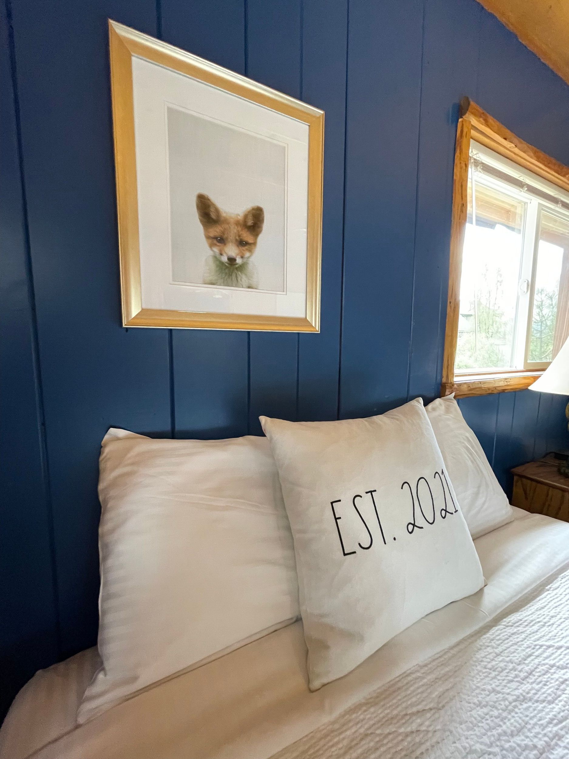 Bedroom with blue wall, framed fox photo, white bedding, 