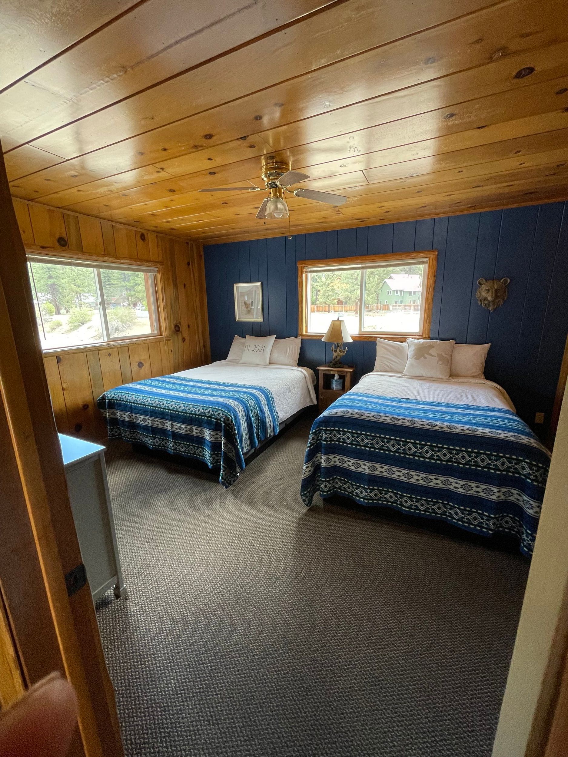 Bedroom with two double beds, blue and white patterned bedding, wood paneling.