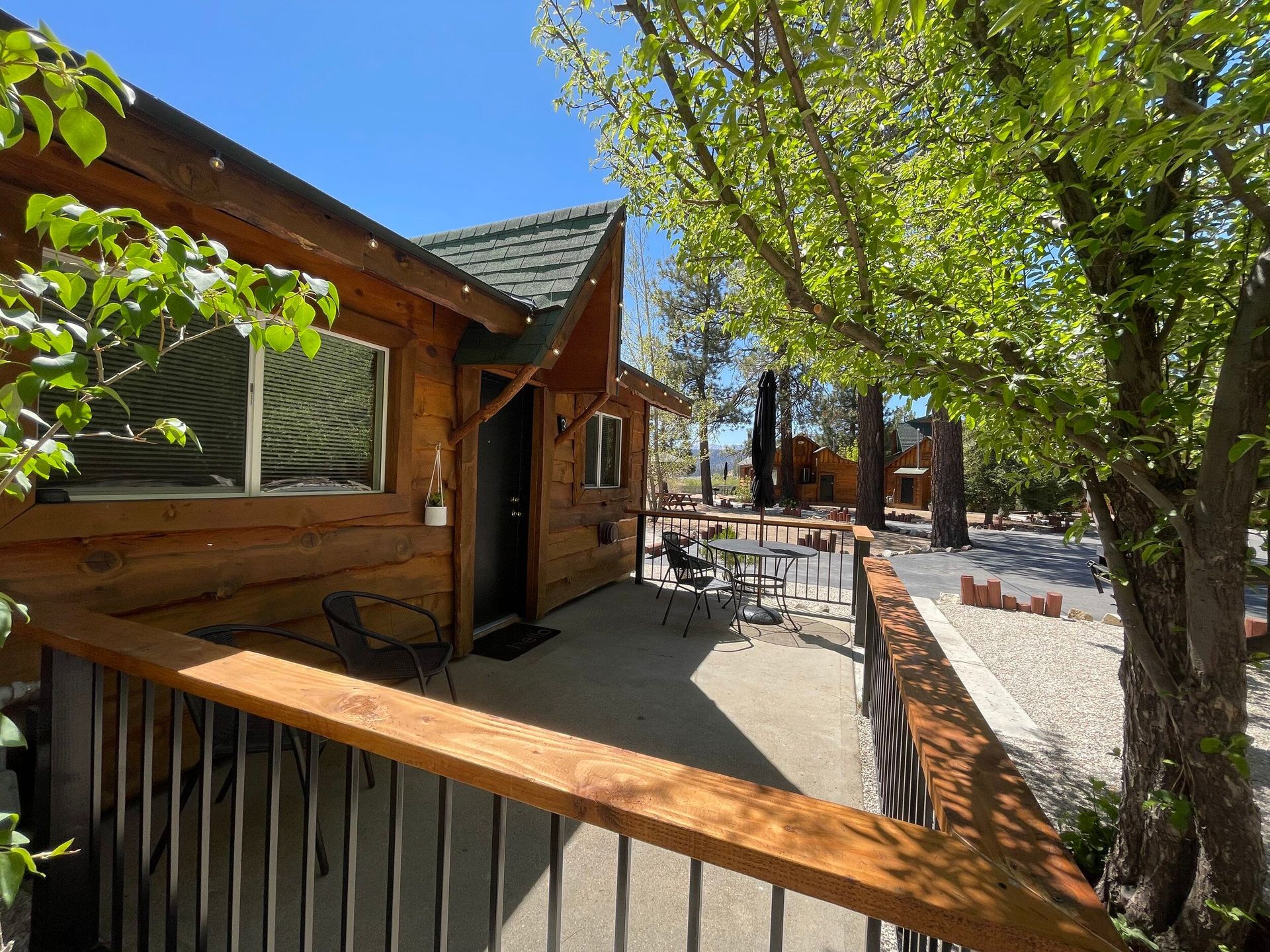 Wooden cabin exterior with a deck, table, and chairs under a clear sky.