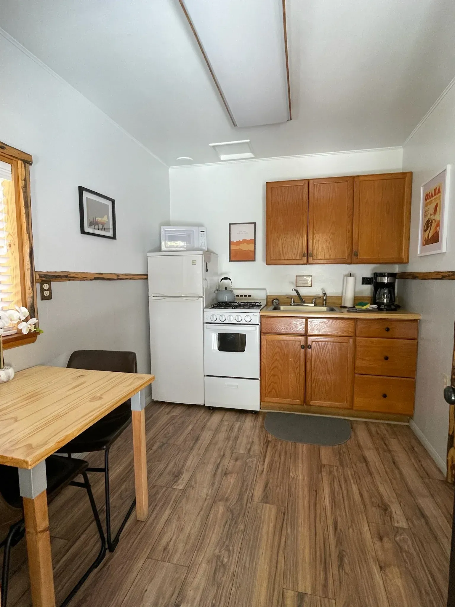 Small cabin kitchen with a stove, fridge, cabinets, and a dining table.