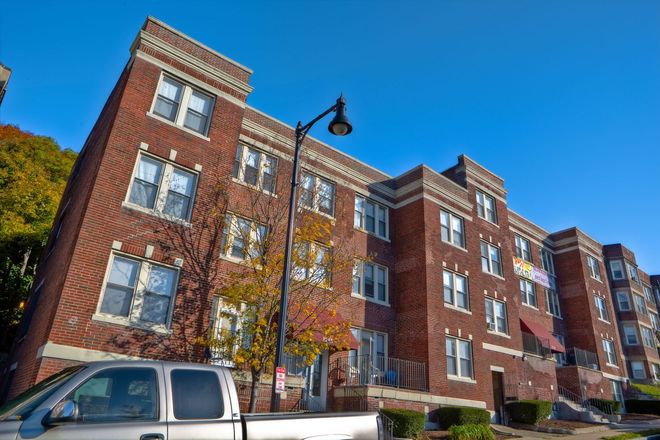 Red brick apartment building with white window frames and a blue sky.