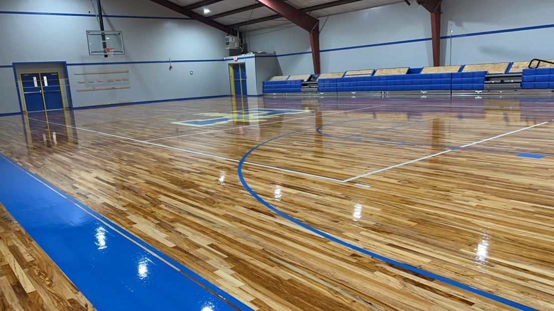 A basketball court with a wooden floor and blue lines.