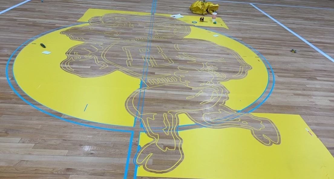 A yellow sign with a lion on it is on a wooden floor.