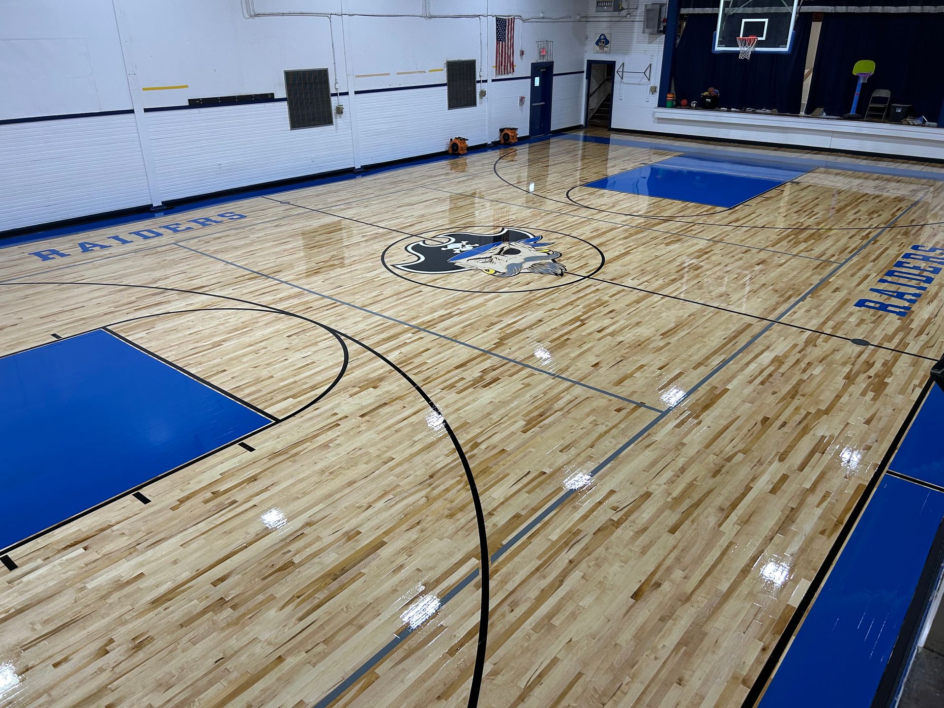 A basketball court with a wooden floor and blue lines