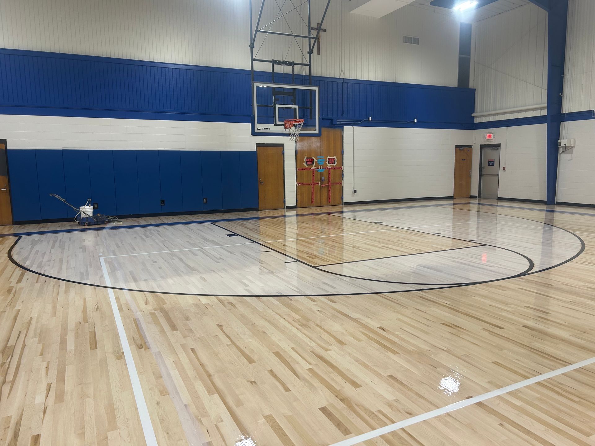 A basketball court with a wooden floor and a basketball hoop.