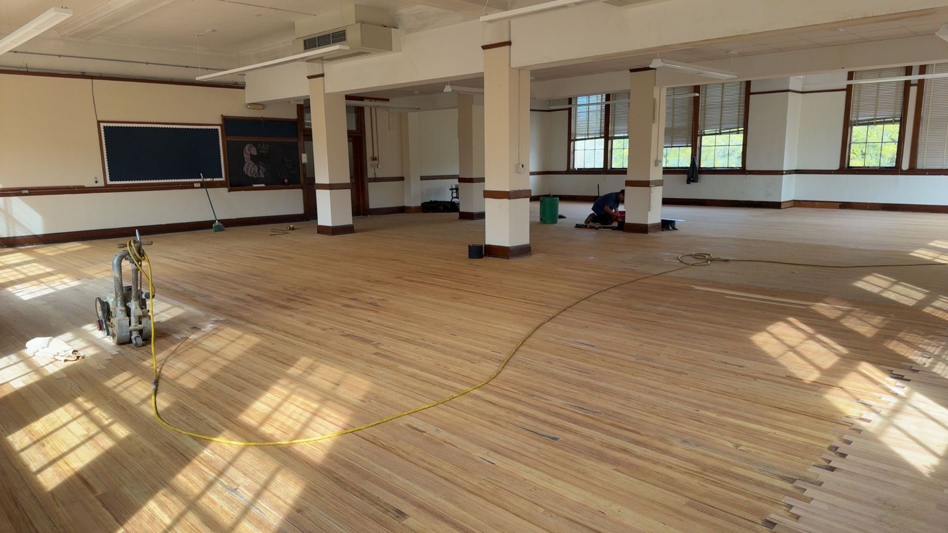 A large empty room with a wooden floor and columns.
