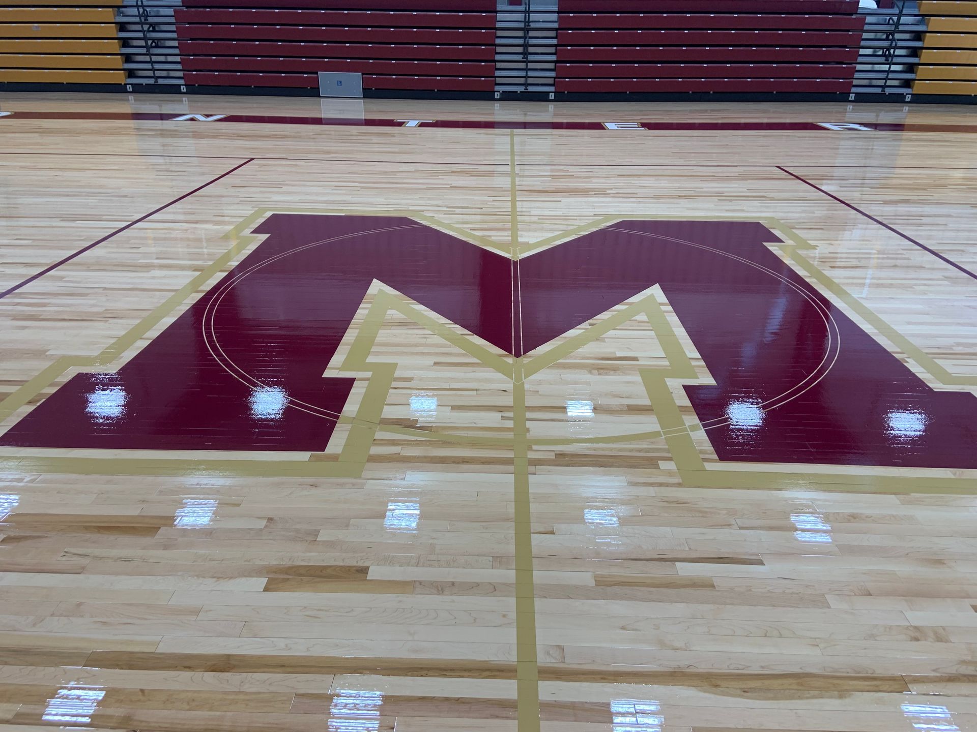 The letter m is painted on the floor of a gym