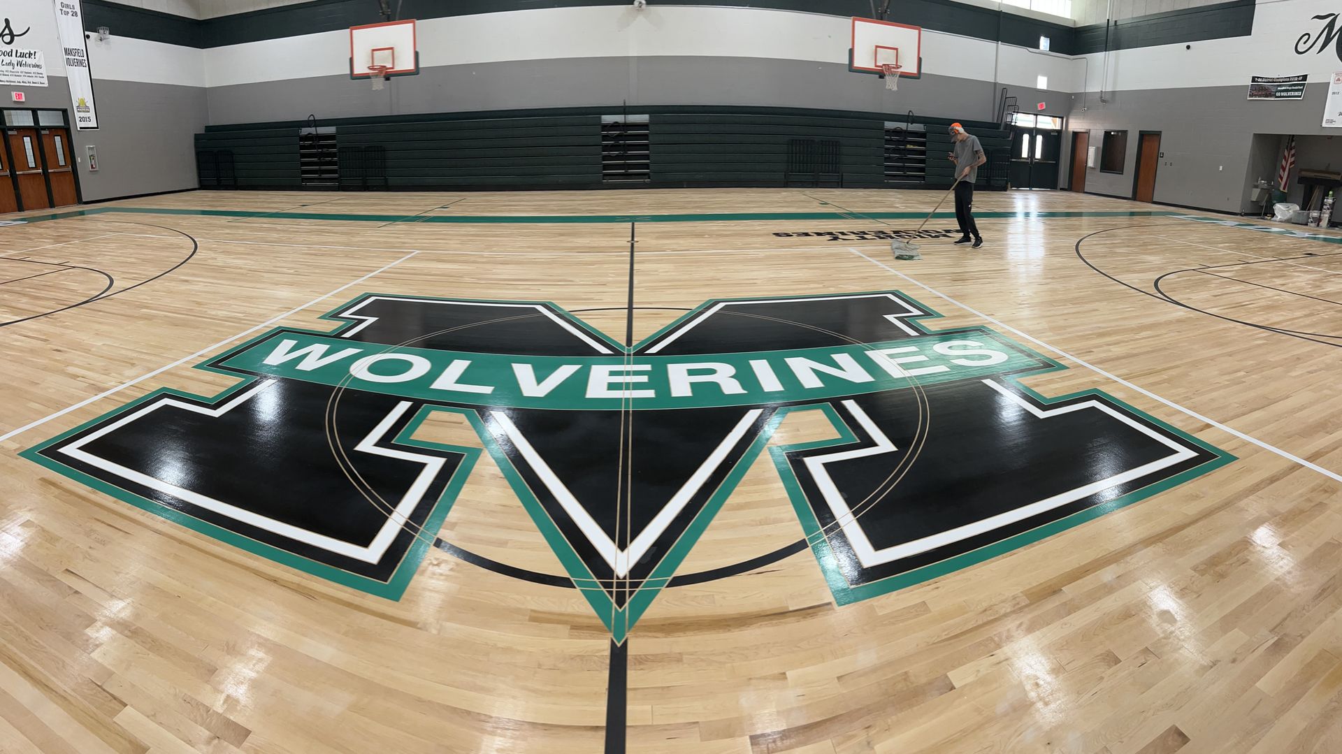 The wolverines logo is on the floor of a basketball court.