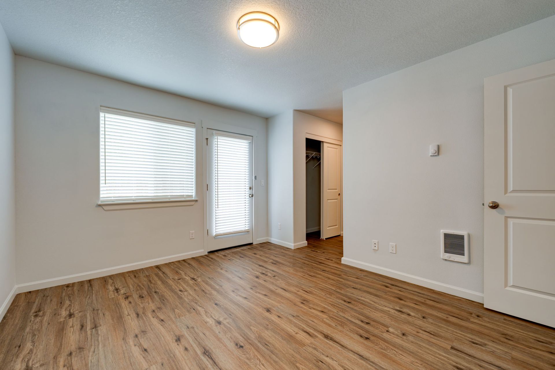 unfurnished ground floor bedroom with view of window, patio door and hallway to bathroom