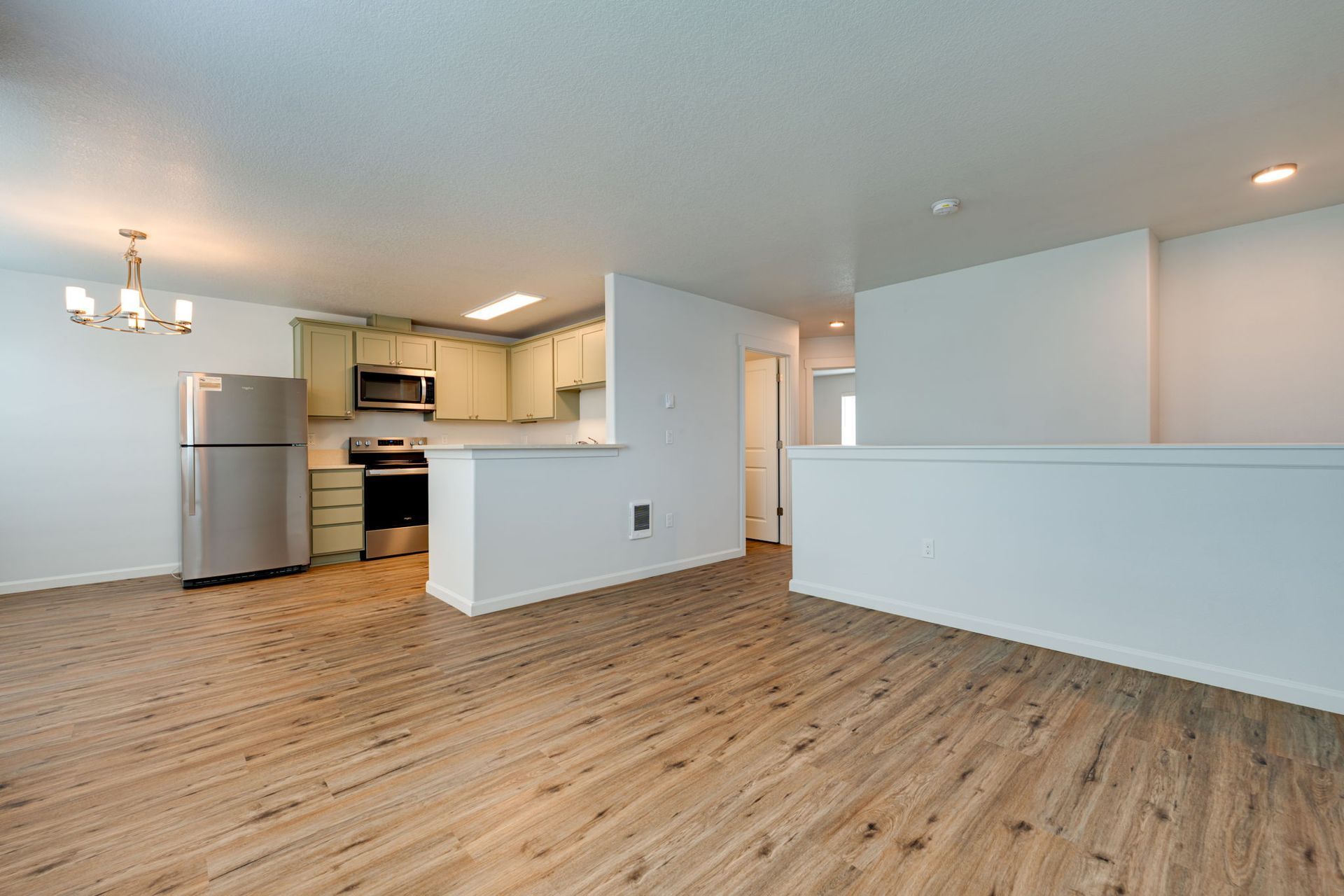 view of unfurnished living room with kitchen and hallway to bedrooms in the background
