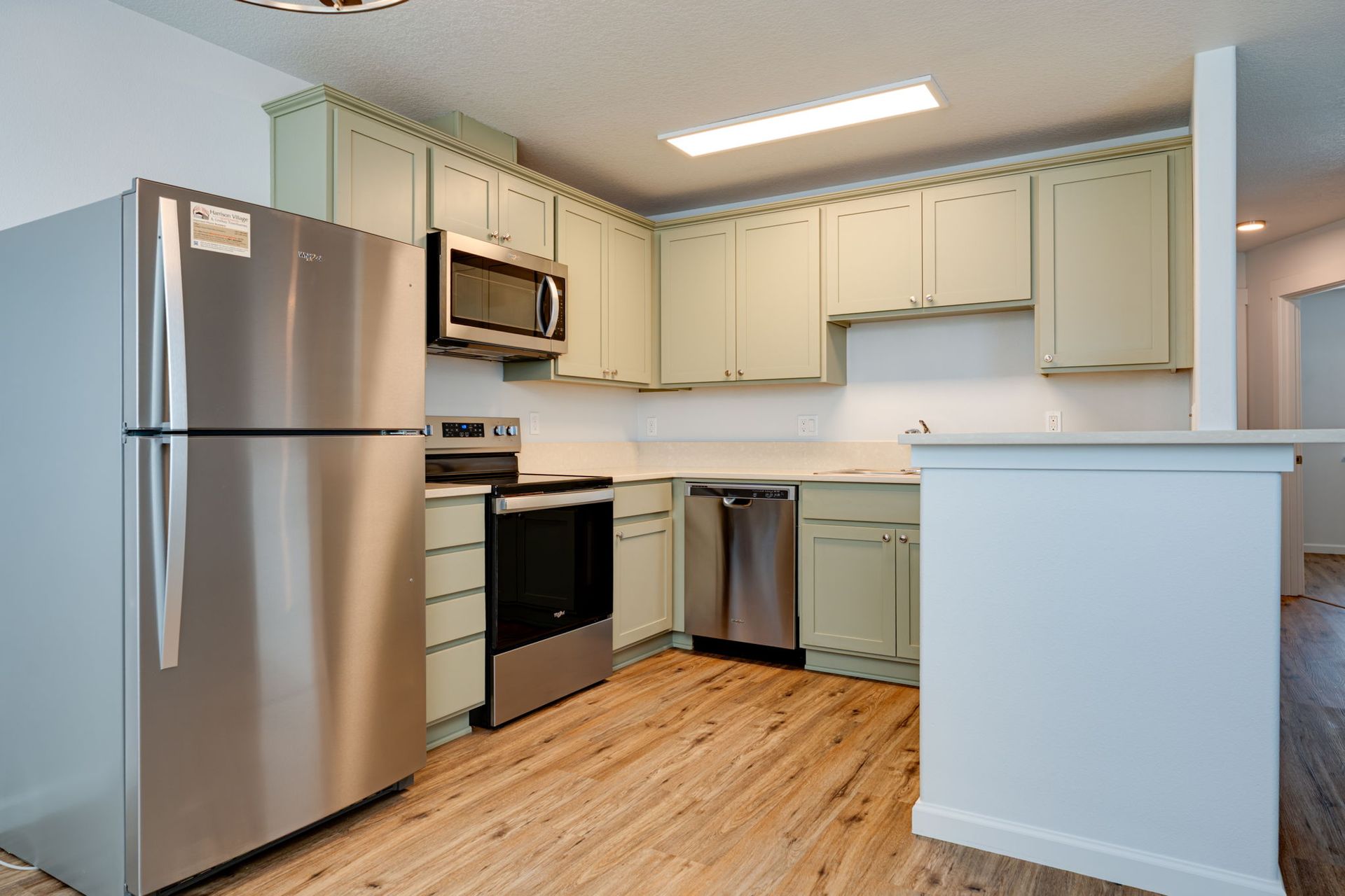 view of kitchen with refridgerator to the left, then range and microhood, then dishwasher.