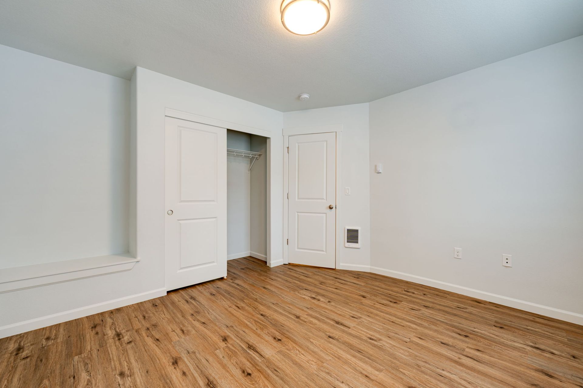 first second-floor bedroom unfurnished with door, closet and sitting nook in the background