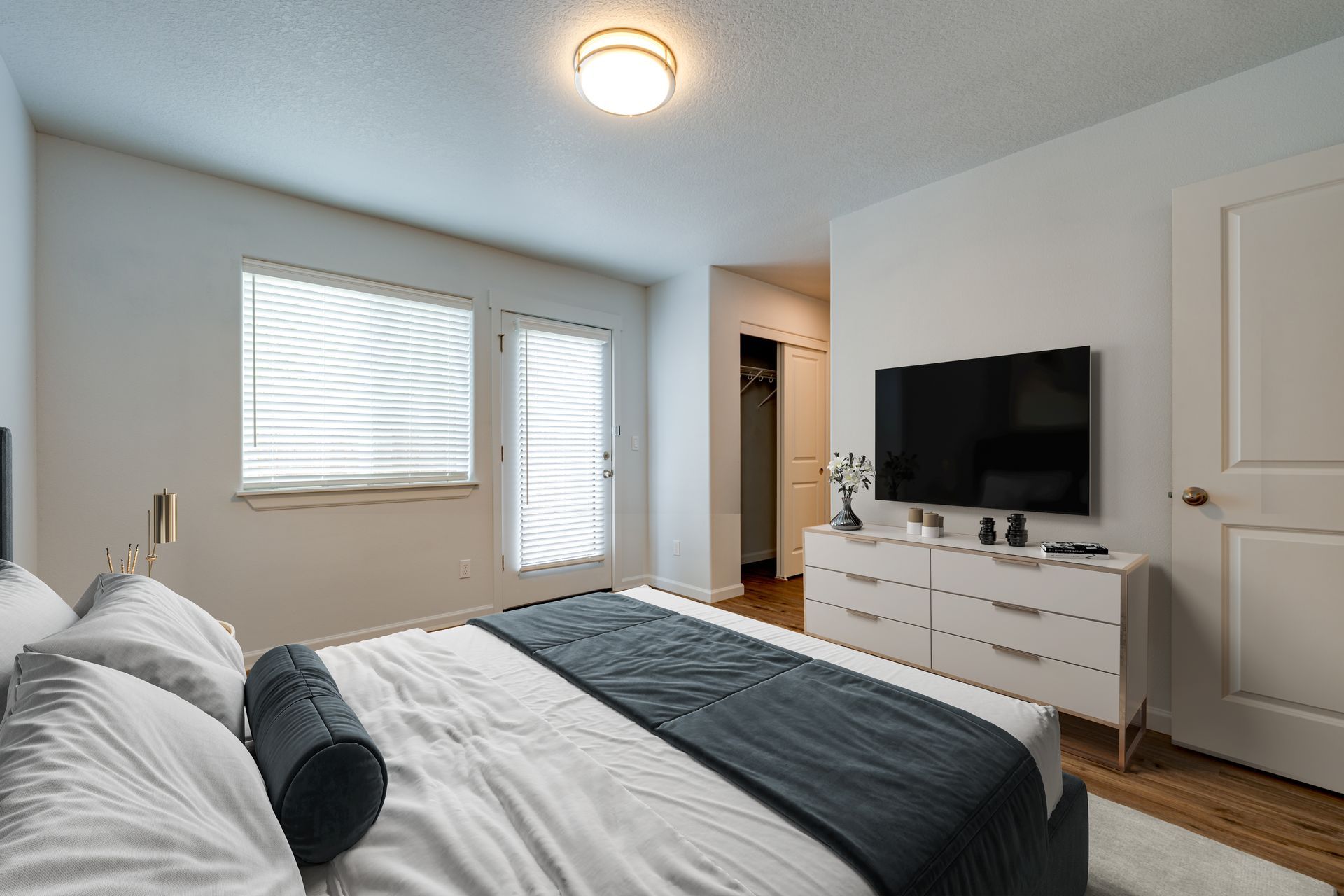 furnished ground floor bedroom with view of window, patio door and hallway to bathroom