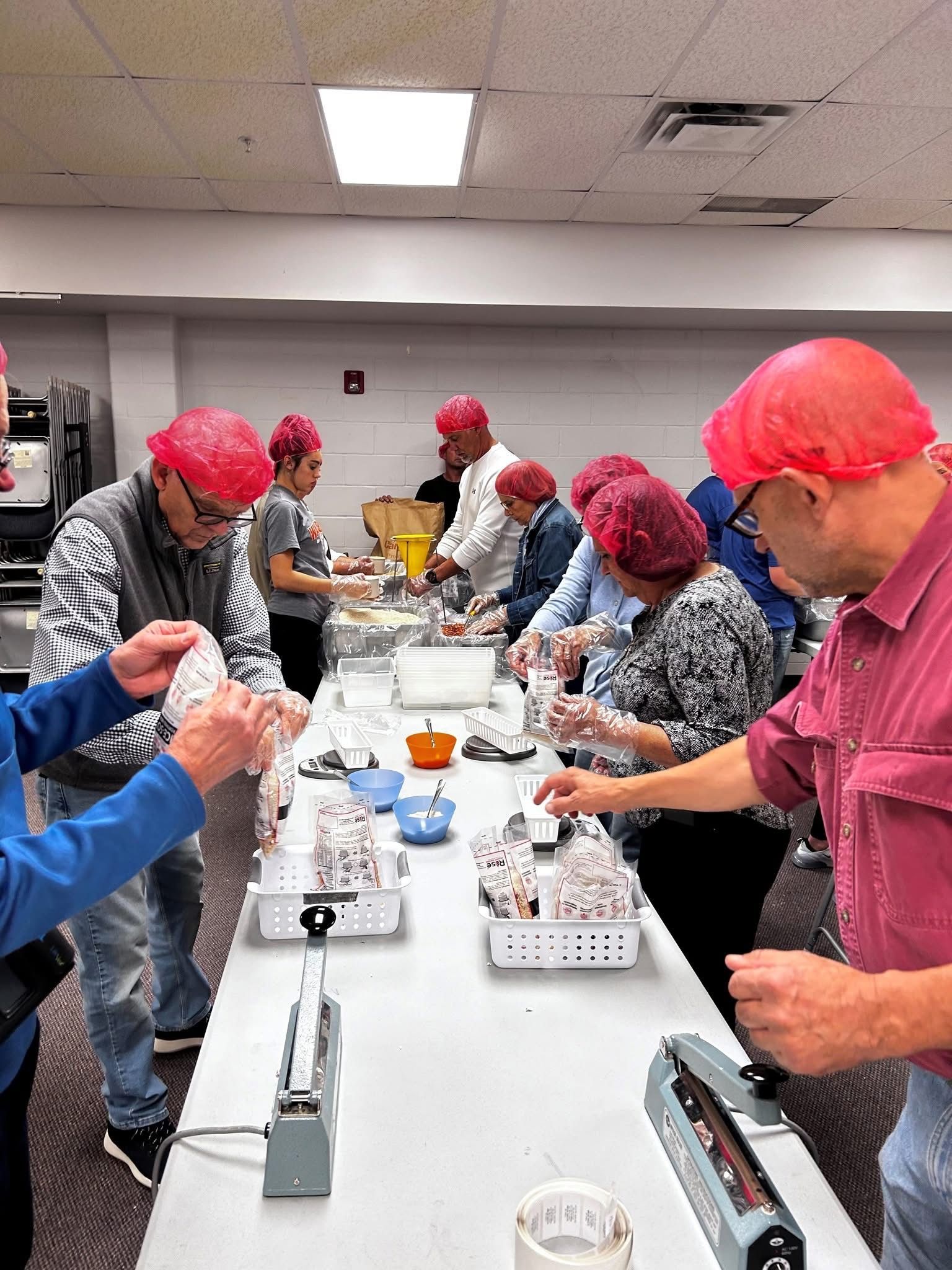 People wearing hairnets packing food at a long table.