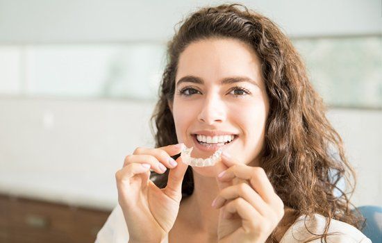 Family Dentistry — Beautiful Patient Holding Orthodontic Retainers in Dental Clinic in Lafayette, IN