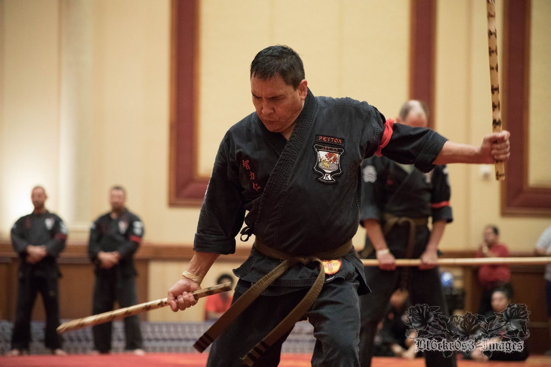 Two men in karate uniforms are posing for a picture in a gym.